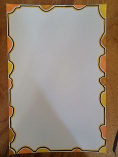 a piece of paper with an orange and white border around it on a wooden table