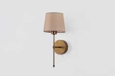 a wall light with a beige shade on it's side and a white background