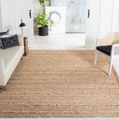 a living room with a couch and chair next to a plant in a pot on the floor