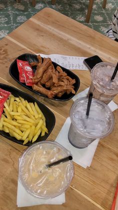 two trays filled with food sitting on top of a wooden table next to drinks