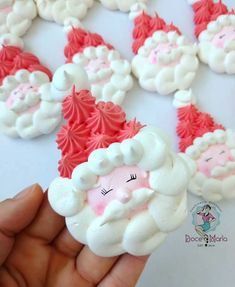 someone is holding up some santa clause cookies on a white table with pink frosting