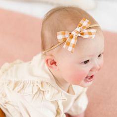 The Baby Bow on Nylon in Mustard Gingham This adorable hair bow is the perfect accessory for your babe! Baby Bows are 3" wide and attached to a comfortable nylon headband. Imported. Cute Adjustable Bow For Summer, Spring Hair Accessories With Matching Headband For Playtime, Playful White Bow With Matching Headband, Cute Adjustable Summer Bow, Playful Adjustable Bow With Matching Headband, Adjustable Playful Bow With Matching Headband, Cute Spring Headband For Playtime, White Headband For Spring Playtime, Adjustable Cotton Bow - Cute Style