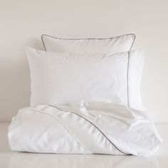 an unmade bed with white sheets and pillows