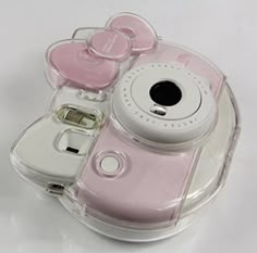 a pink and white camera sitting on top of a glass case with its lid open