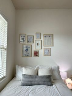 a bed with white sheets, pillows and pictures on the wall above it's headboard