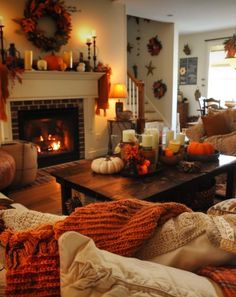 a living room decorated for fall with candles and pumpkins on the fireplace mantel