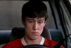 a young man sitting in the passenger seat of a car