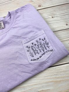 Comfort Colors 6030 pocket tee with flowers and 'to live with the hope of it all' embroidered on the pocket. *POCKET IS NOT FUNCTIONAL DUE EMBROIDERY* Shirt pictured is orchid with black thread. Colors may vary from screen to screen. The relaxed fit shirt is 100% ring spun cotton and made with OEKO-TEX certified dyes. Embroidered Cotton Lavender Top, Embroidered Lavender Cotton Top, Embroidery Shirt, Shirt Embroidery, Black Thread, The Hope, Pocket Tee, Comfort Colors, Workout Shirts