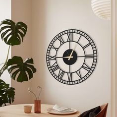 a clock that is on the wall next to a table with a potted plant