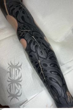 a man's arm covered in black ink with vines and leaves on it,