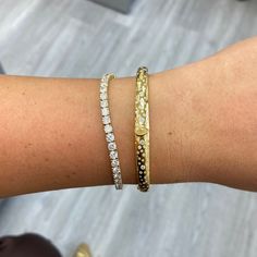 a woman's arm with two bracelets on it and one is wearing a diamond bracelet