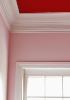 a red painted ceiling and window in a pink room with white trim on the walls