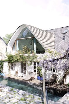 a house with a pool in front of it next to a tree and some bushes