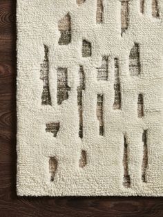 a white rug with brown and black designs on it, sitting on a wooden floor