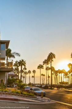 an apartment building with palm trees in the background and cars parked on the street below