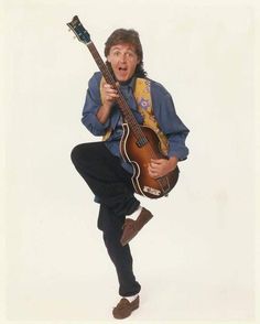 a man holding a guitar while standing on one leg