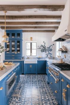 a kitchen with blue cabinets and white counter tops, gold accents on the backsplash