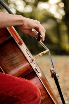 a close up of a person holding an instrument in their left hand and playing the cello