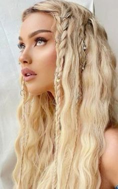 a woman with long blonde hair and braids in front of a white wall wearing a blue dress