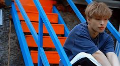 a young man sitting on top of a blue and orange chair next to an orange wall