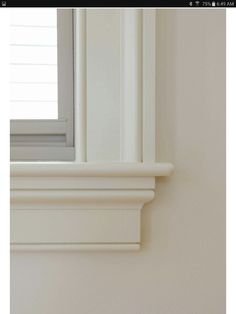 the corner of a window sill is shown with a white frame and molding