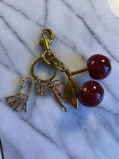 two red glass balls on a gold metal keychain with charms attached to them