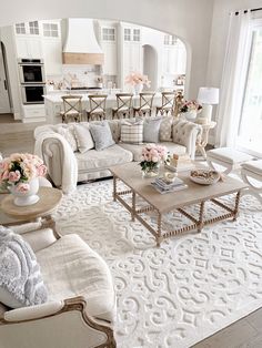 a living room filled with white furniture and lots of flowers on top of the coffee table