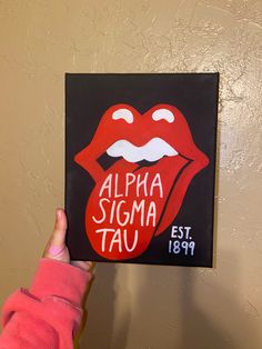 a person holding up a sign with the words alpha sigma tau on it