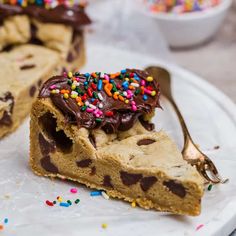 a piece of cake with chocolate frosting and sprinkles on top is sitting on a plate