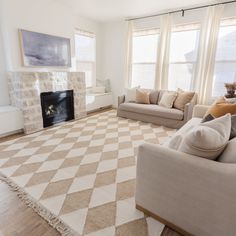 a living room with two couches and a rug in front of a fire place