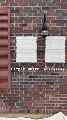 a brick wall with two windows and the words simply white alligator written on it