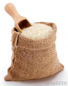 a wooden spoon in a burlock filled with white rice on a white background