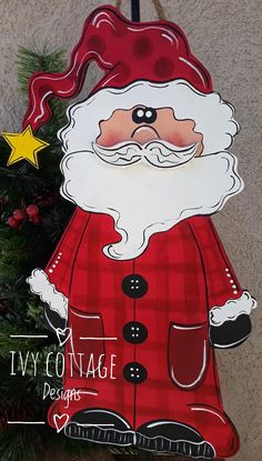 a wooden sign with a santa clause on it's face next to a christmas tree