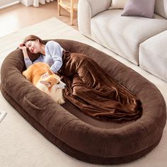 a woman laying on top of a brown dog bed