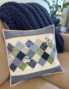 a blue and green patchwork pillow sitting on top of a couch