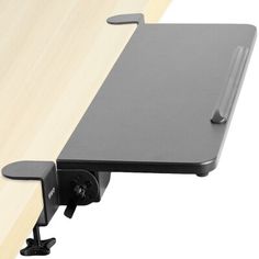 a computer desk with a laptop on it's back end and a mouse holder attached to the wall