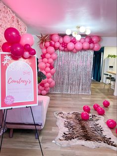 a room with pink balloons and a sign