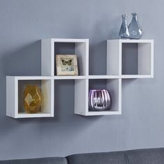 three white cube shelves with vases on each shelf and one empty glass bottle in the middle