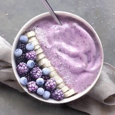 a bowl filled with berries and bananas next to a spoon