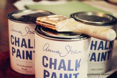 two cans of chalk paint sitting on top of a table