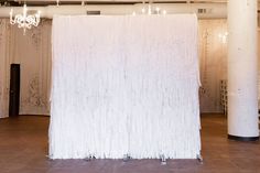 a white backdrop is set up in the middle of an empty room with chandeliers hanging from the ceiling