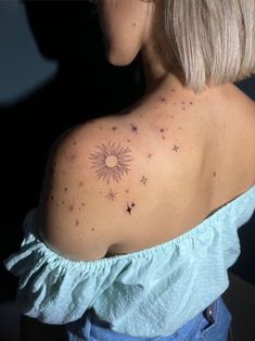 the back of a woman's shoulder with small stars on her left arm and sun in the middle