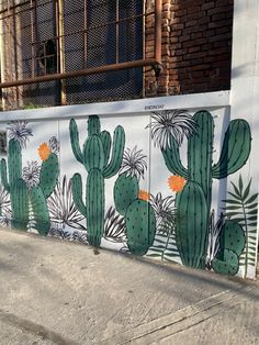 there is a mural on the side of a building that has cactuses painted on it