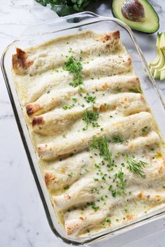 an enchilada is in a baking dish with avocado on the side