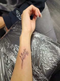 a woman's arm with a small flower tattoo on the left side of her arm