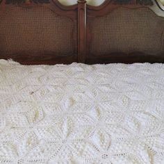 a crocheted bedspread on top of a wooden headboard and foot board