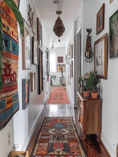 a long hallway with pictures on the wall and rugs hanging from the ceiling in front of it