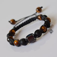 "Adjustable and trendy, you will never want to take this gemstone beaded bracelet off. Featuring a Hematite cube as its centerpiece, this beaded bracelet is made with natural 8 mm Tigers Eye and matte Black Onyx beads. This piece of mens jewelry is strung on a waxed cord and finishes off with an adjustable closure adorned with two Tigers Eye stopper beads. Hematite is said to stimulate mental activity, balance yin and yang energies and dissolve negative energies. It is considered a grounding and Two Tigers, Aries And Aquarius, Shamballa Bracelets, Bracelet Christmas, Hematite Bracelet, Bracelet Mens, Bracelet Crystal, Jewelry Beaded, Gemstone Beaded Bracelets