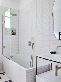 a white tiled bathroom with black and white floor tiles on the shower wall, tub, and sink