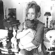 a woman holding a baby in her arms while sitting on a chair next to a table